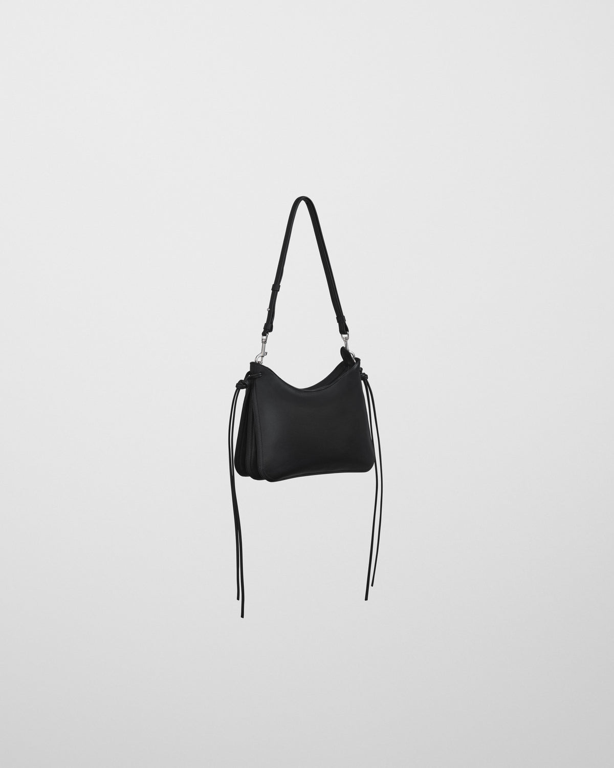 Bolso Gig negro Phoebe Philo en vista lateral, cordones colgantes y cierre plateado en bandolera ajustable.