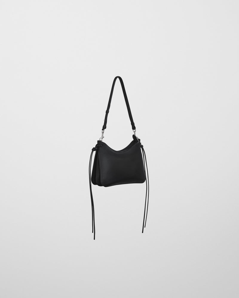 Bolso Gig negro Phoebe Philo en vista lateral, cordones colgantes y cierre plateado en bandolera ajustable.