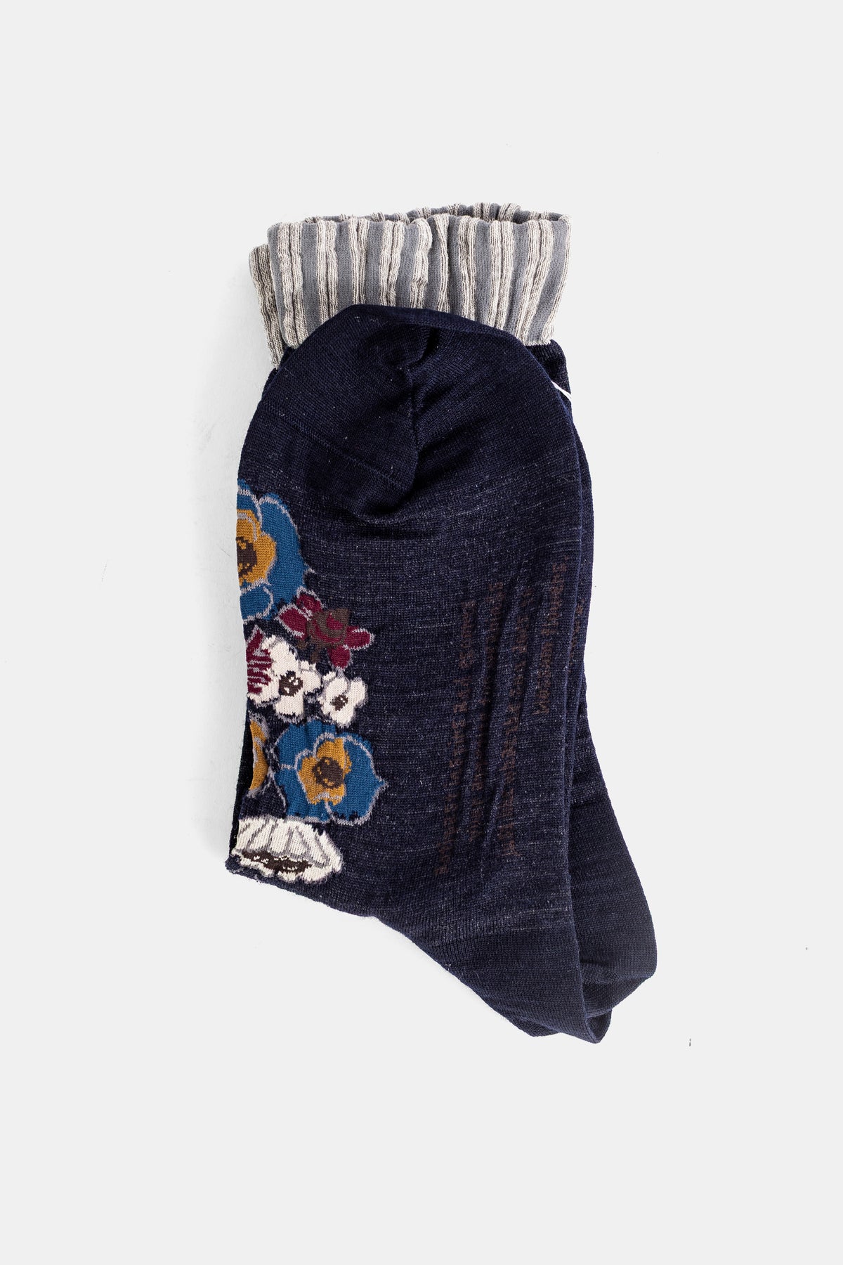 Antipast chaussettes en maille marine pliées, broderies florales bleues, ocres et bordeaux sur le devant