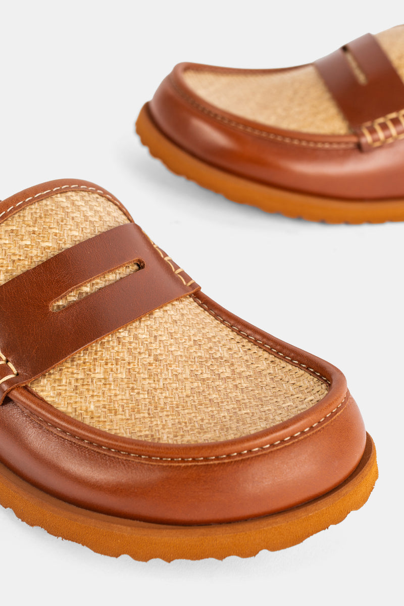 Dettaglio del sabot Birkenstock 1774 Naples con tomaia in rafia intrecciata e profilo in pelle cognac impunturata