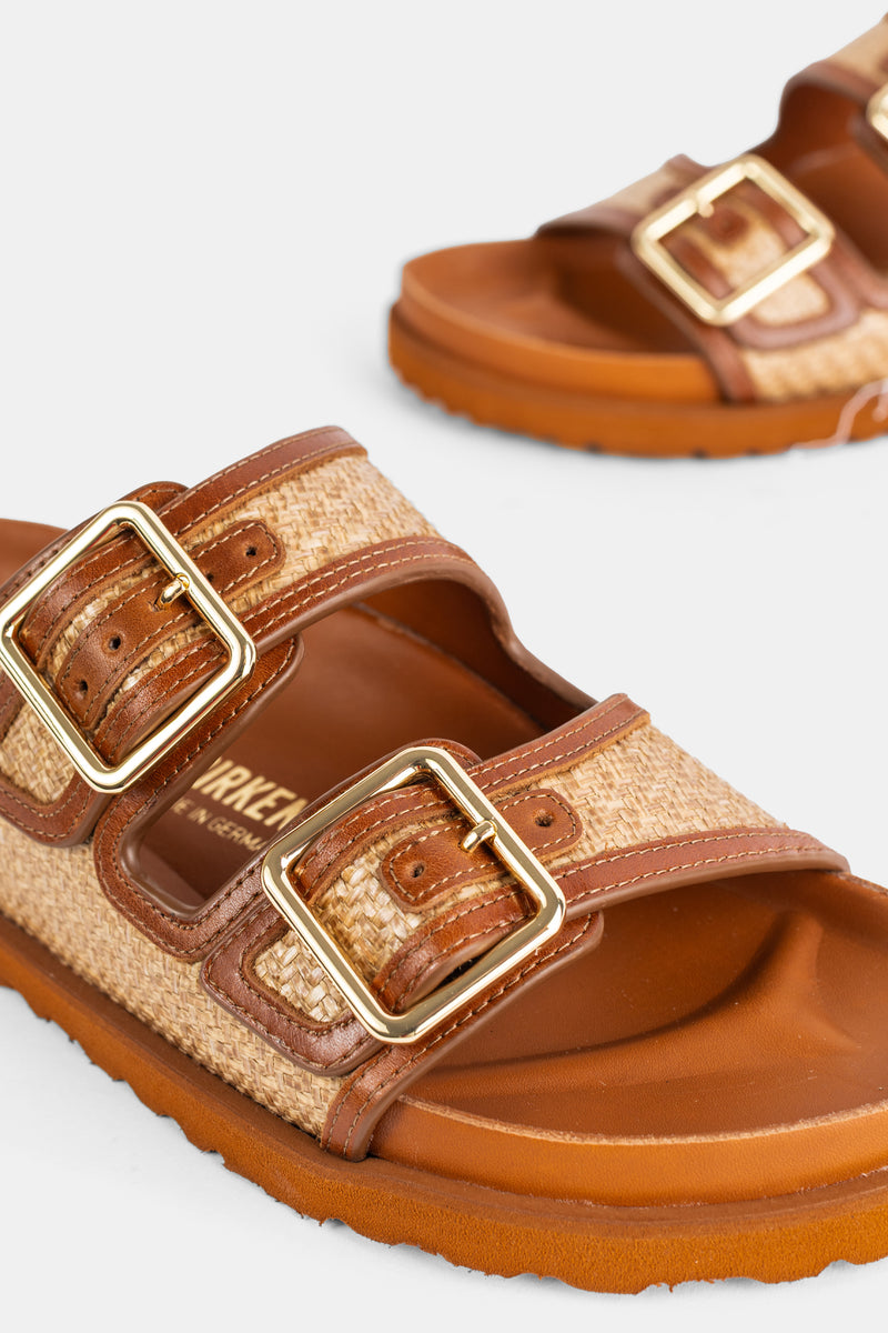 Dettaglio delle fibbie quadrate dorate dei sandali Arizona Ginger Birkenstock 1774 su cinturini in rafia e pelle.