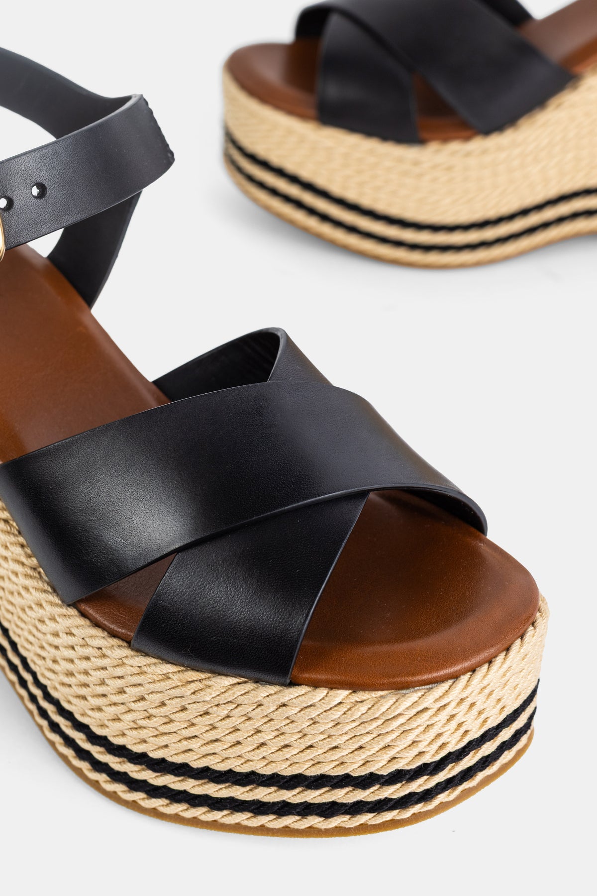 Detailaufnahme der Chloé Sand Sandalen mit gekreuztem schwarzem Leder auf einer gestreiften Juteplattform.