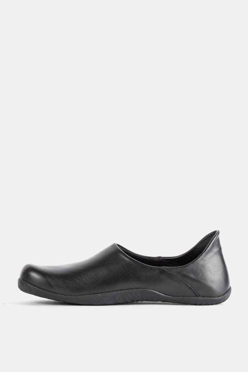 Side profile of the Demon Dalmara unisex black leather mule with a flat Vibram sole and laceless upper.