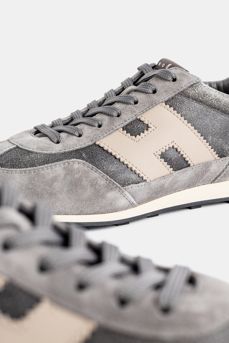 Dettaglio sneaker uomo Hogan: cuciture festonate, H beige, camoscio grigio e pannello antracite lucido