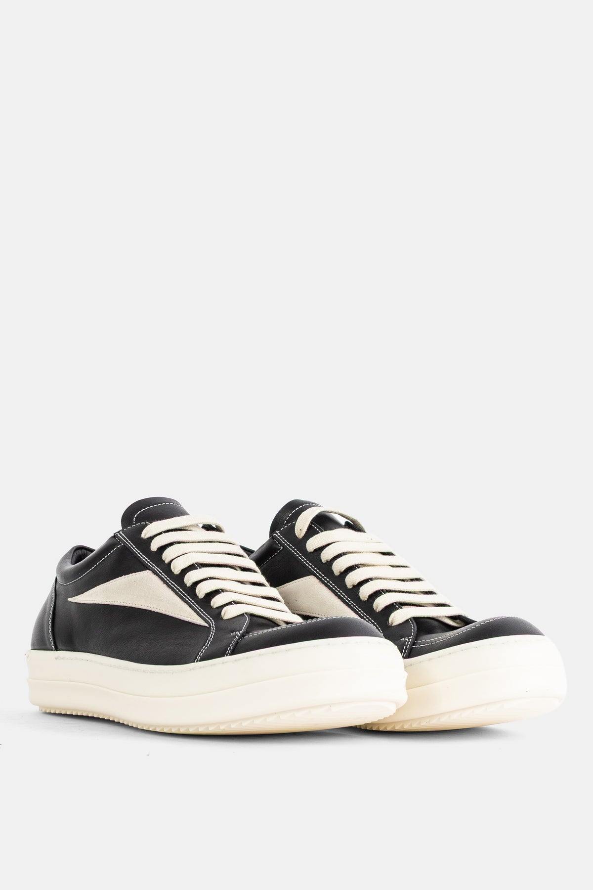 Rick Owens low-top black leather sneakers with visible white topstitching and an ivory-colored suede tongue