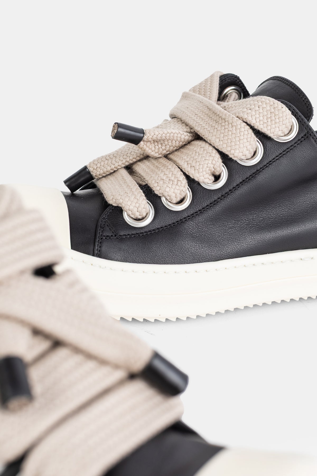 Rick Owens Jumbolace Low gros plan lacets tressés beige oversize et œillets métal argenté sur cuir noir souple