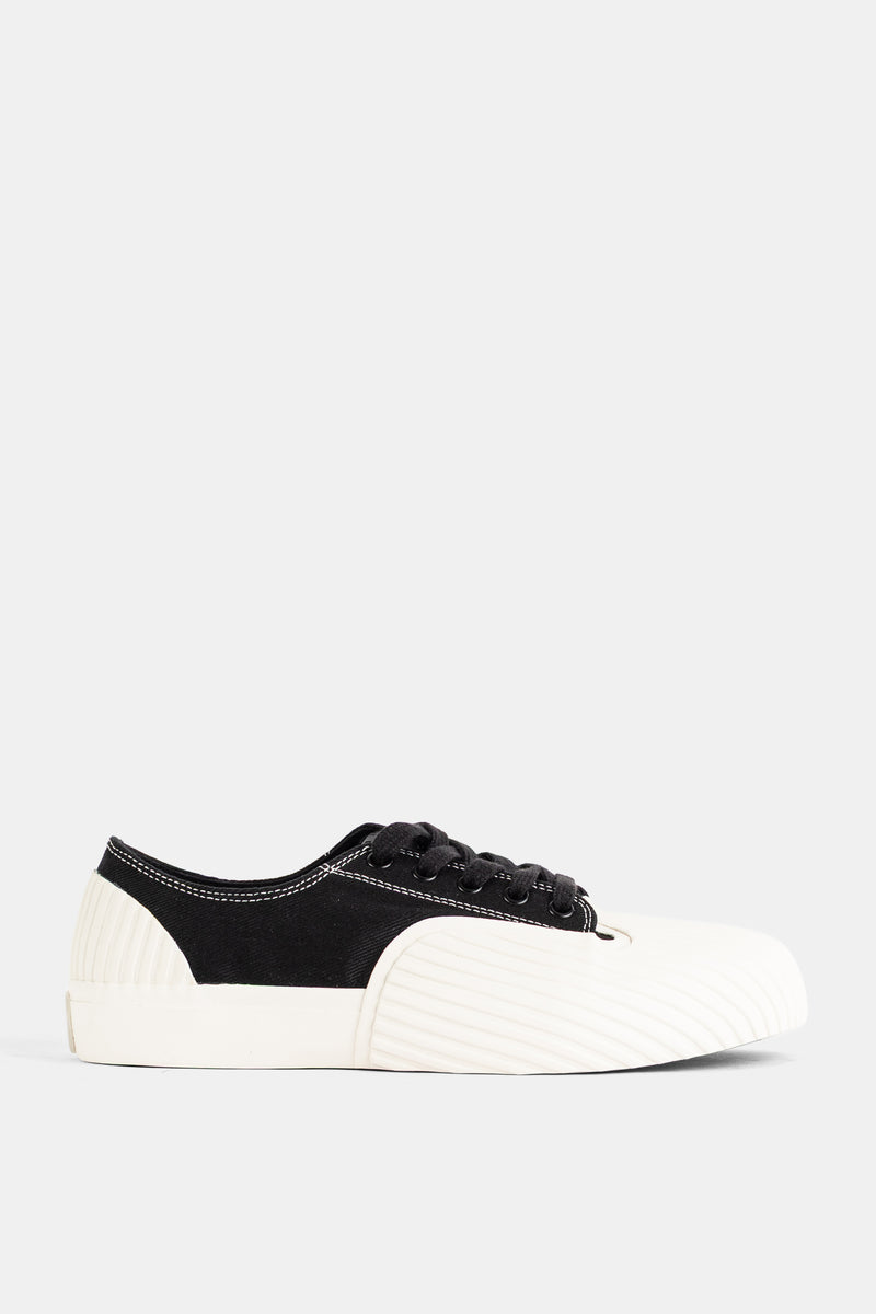 Unformed Prototype 01 flacher Unisex-Sneaker aus schwarzem Canvas mit skulpturaler elfenbeinweißer Gummisohle.
