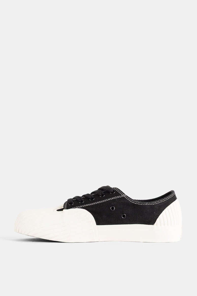 Seitenprofil des Unformed Prototype 01 Sneakers aus schwarzem Canvas mit weißen Nähten und elfenbeinweißer Gummi-Ferse.