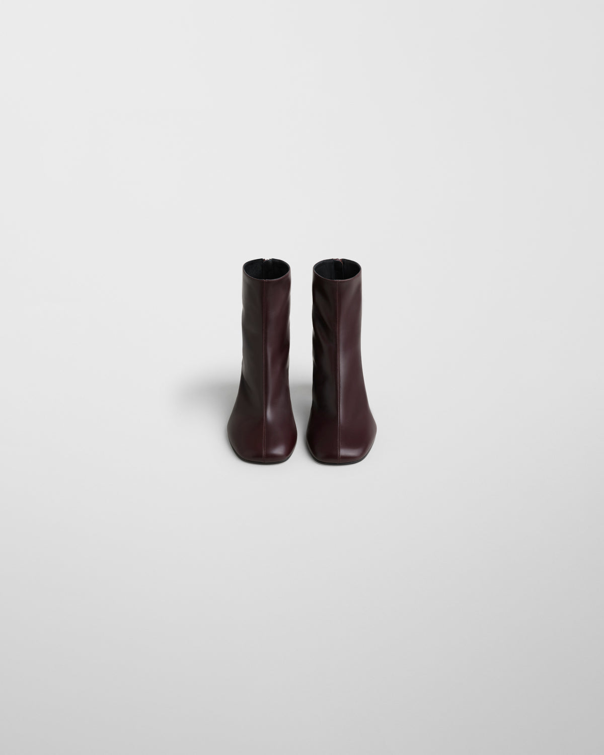 Vista frontal do par de botins Phoebe Philo Tug em pele bordeaux, silhueta reta e simétrica para mulher.
