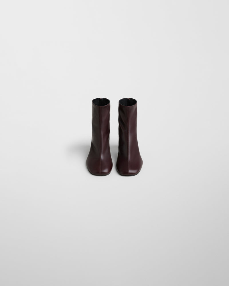 Vista frontal do par de botins Phoebe Philo Tug em pele bordeaux, silhueta reta e simétrica para mulher.
