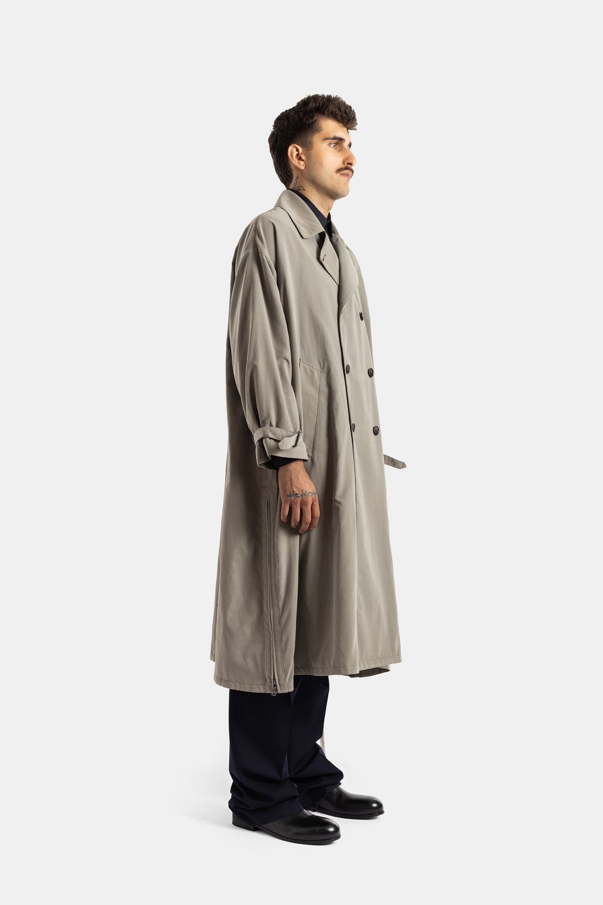 Giorgio Armani trench homme coupe longue vue de profil, silhouette ample en gabardine kaki, poignets boutonnés
