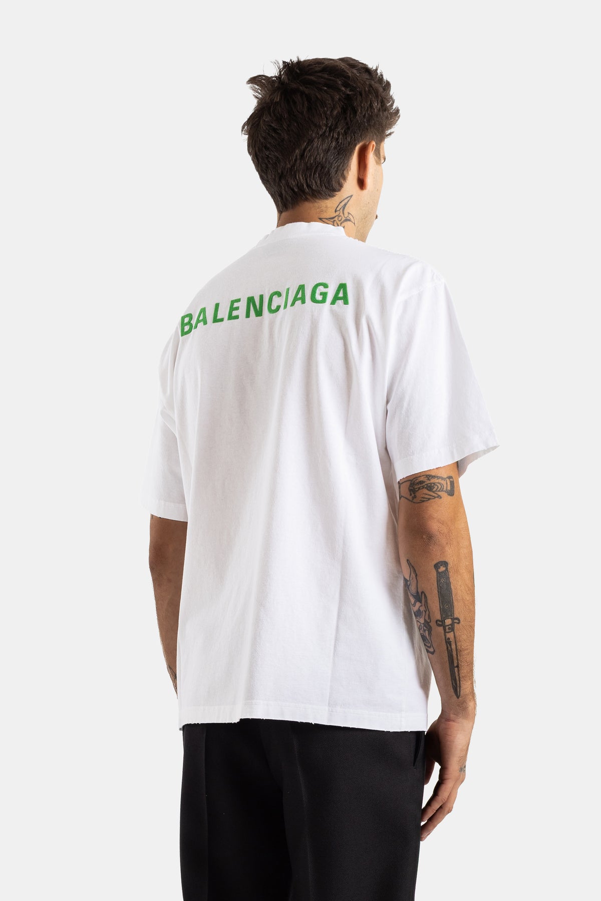 Oversized witte Balenciaga heren T-shirt vanaf de achterkant gezien met groen logo en tatoeages op de arm.