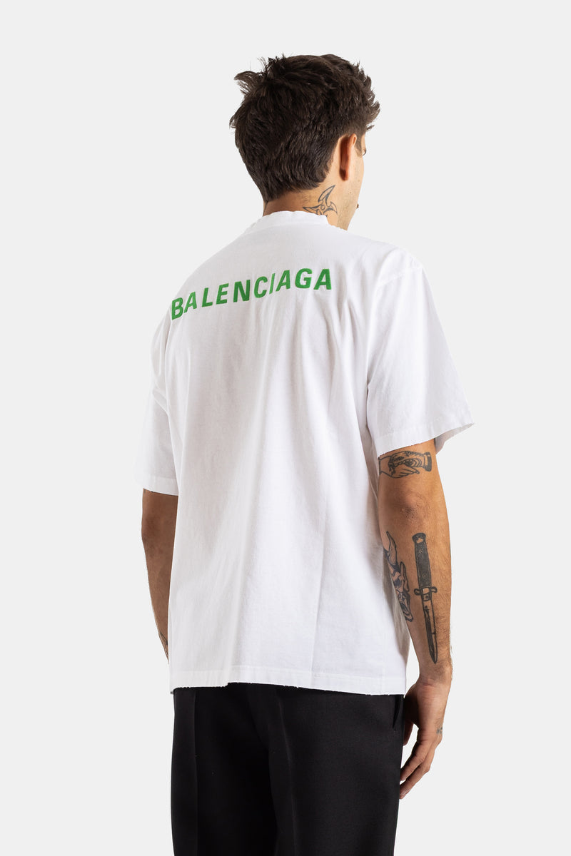 Oversized witte Balenciaga heren T-shirt vanaf de achterkant gezien met groen logo en tatoeages op de arm.
