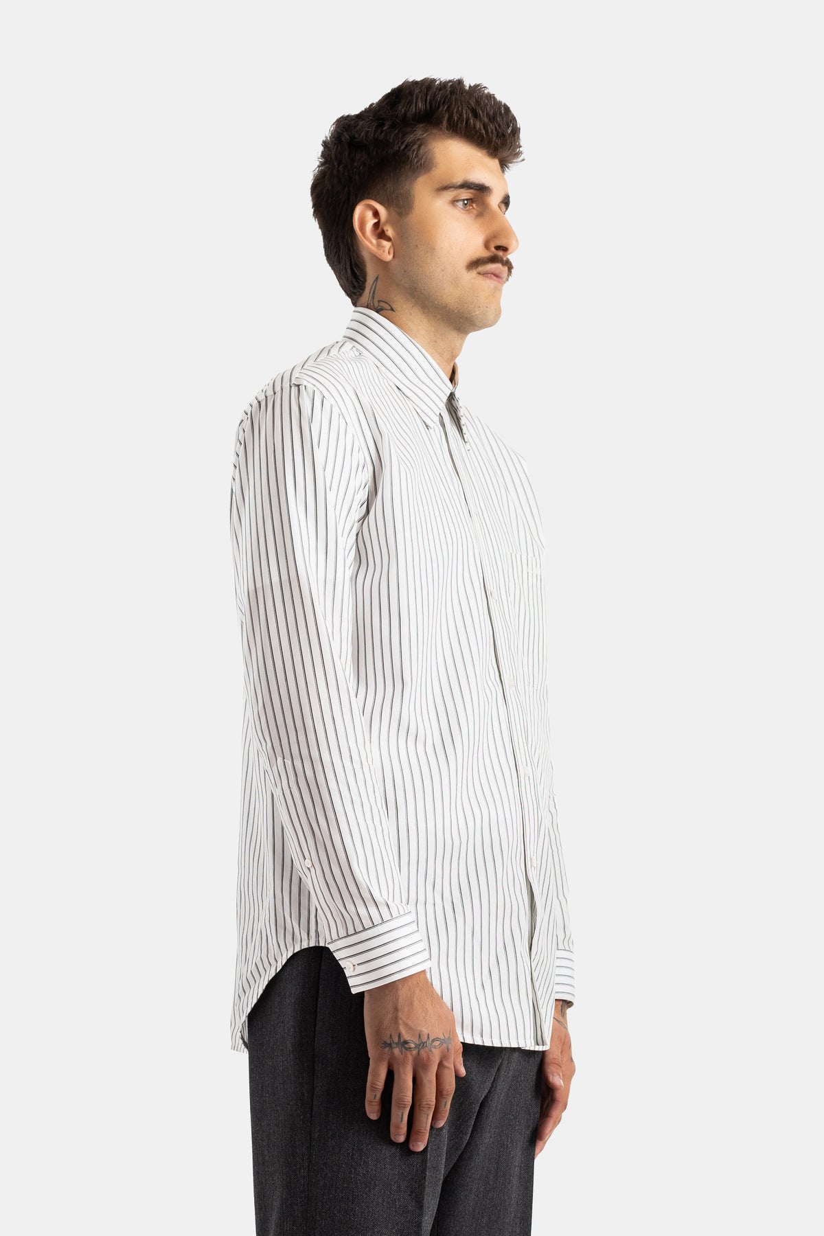 Camicia da uomo Balenciaga a righe verticali nere, vista di profilo, taglio oversize e polsini con bottoni.