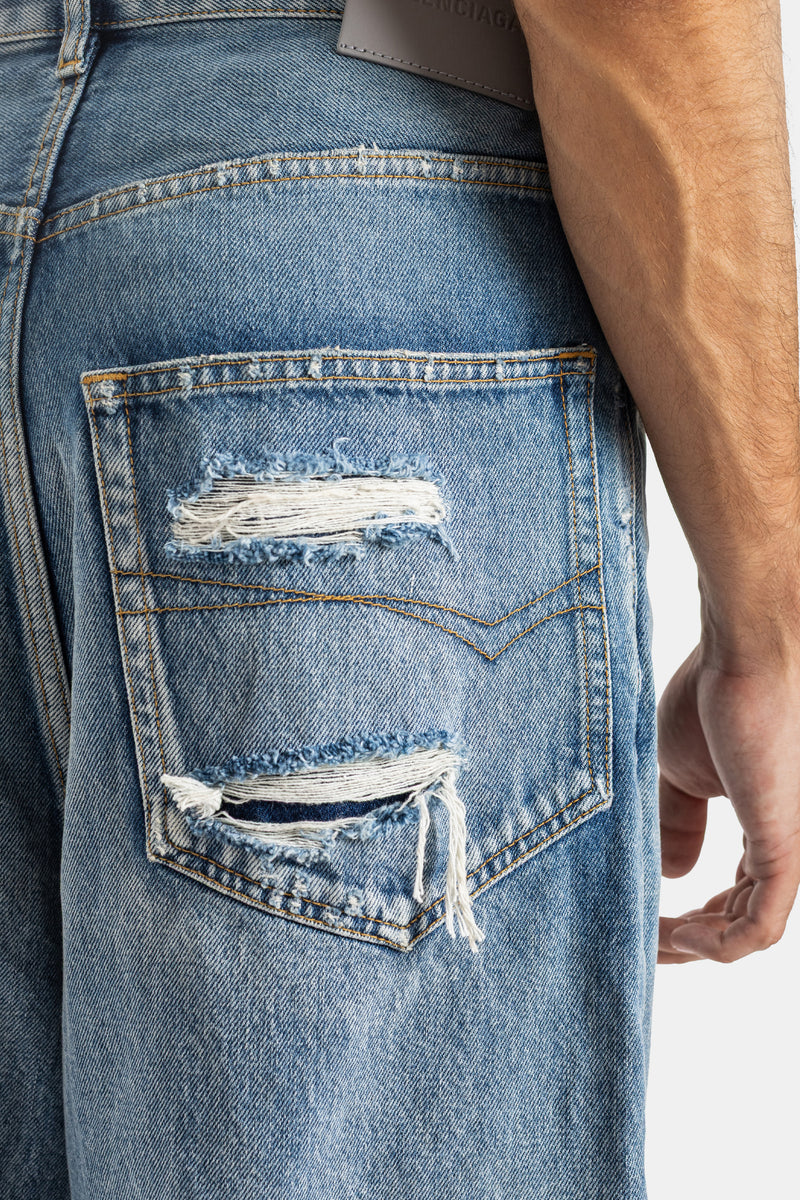 Balenciaga jean Round Fit poche arrière déchirée en gros plan avec surpiqûres dorées et effilochures denim homme