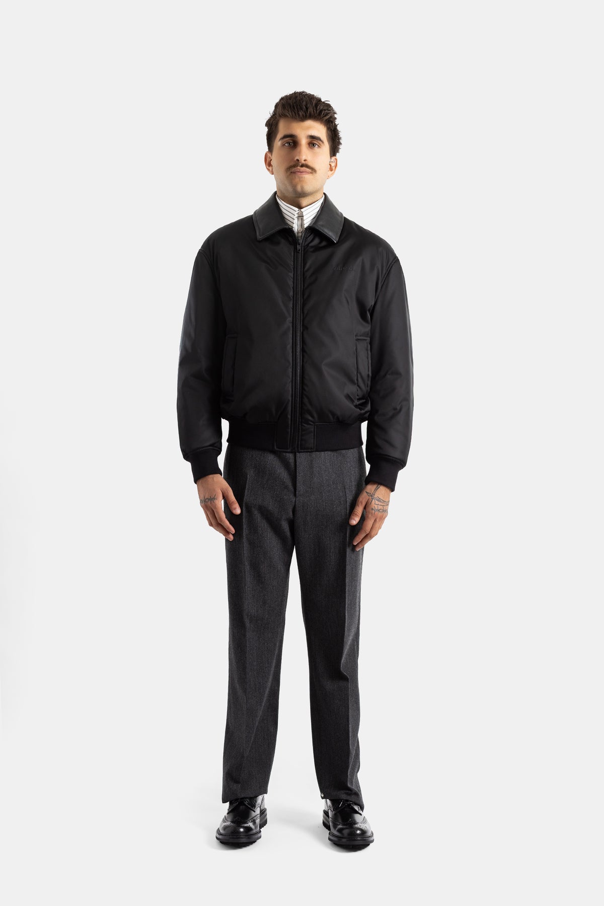 Pantaloni sartoriali uomo Balenciaga grigio scuro con bomber nero e scarpe derby, look elegante e casual