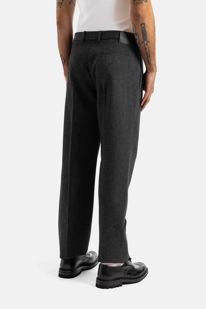 Dettaglio posteriore pantaloni sartoriali Balenciaga grigio scuro, cintura in pelle e scarpe brogue nere