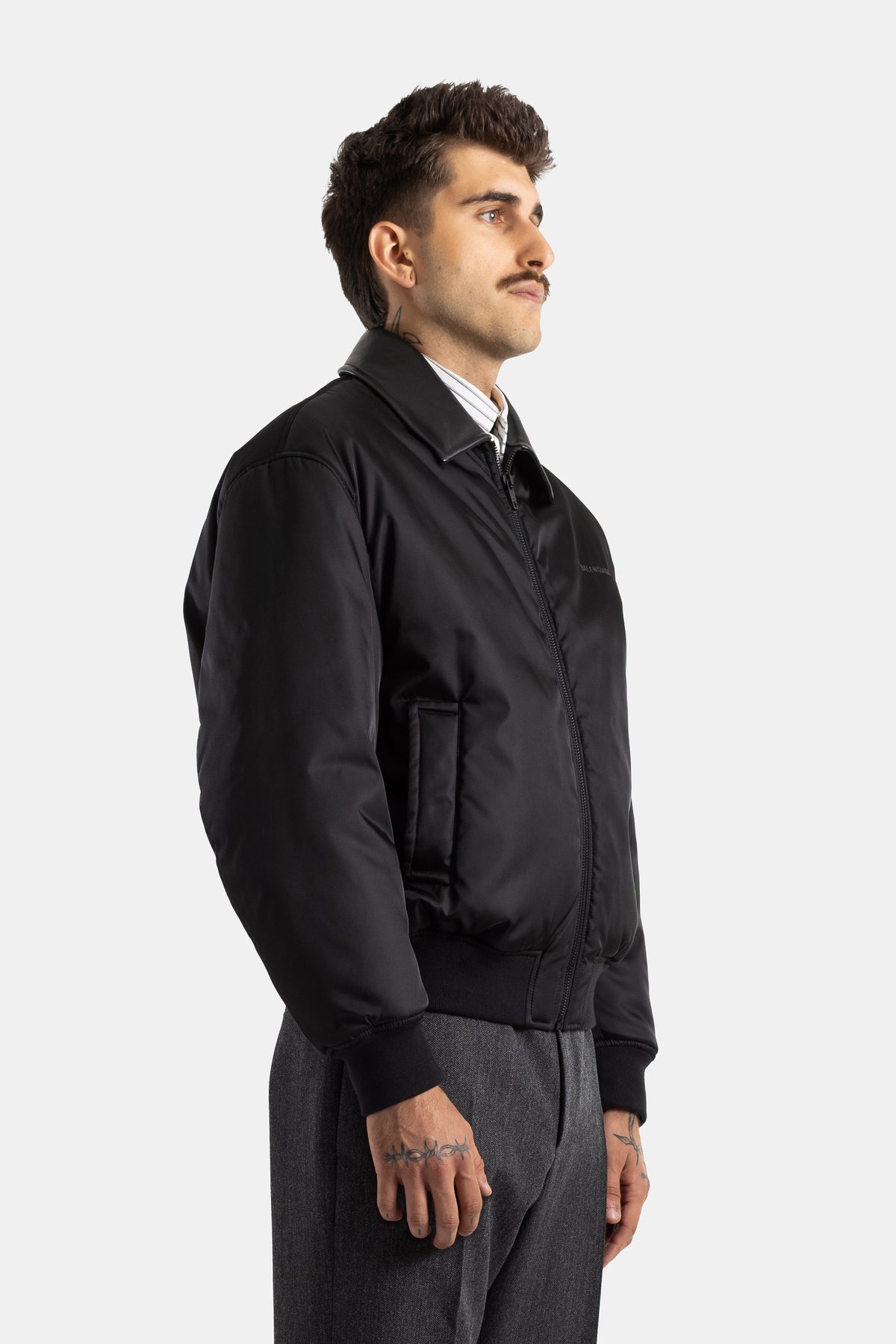 Bomber Balenciaga Cocoon negro de perfil con cremallera, bolsillo de parche y pantalón gris jaspeado para hombre.