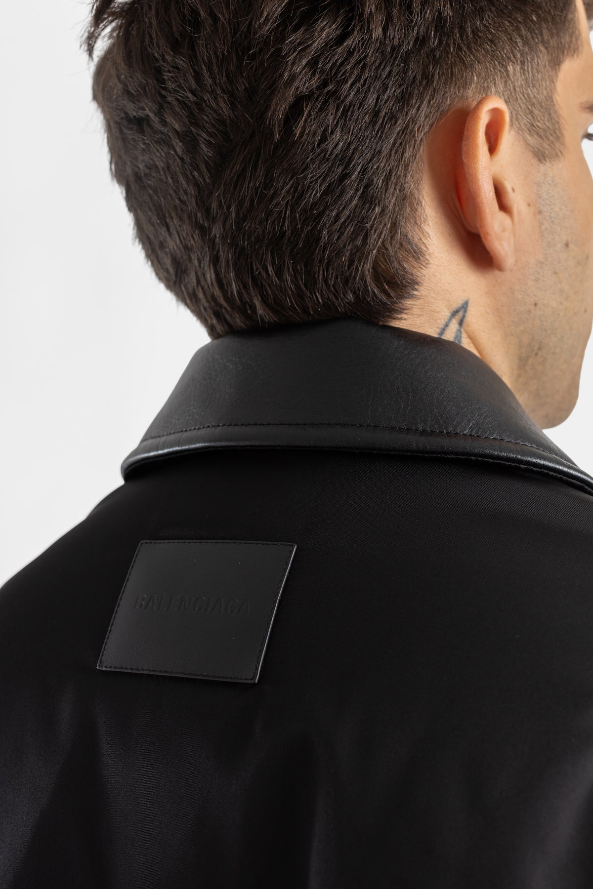 Vista de la nuca del bomber Balenciaga Cocoon negro con cuello de piel, parche de logo en relieve para hombre.
