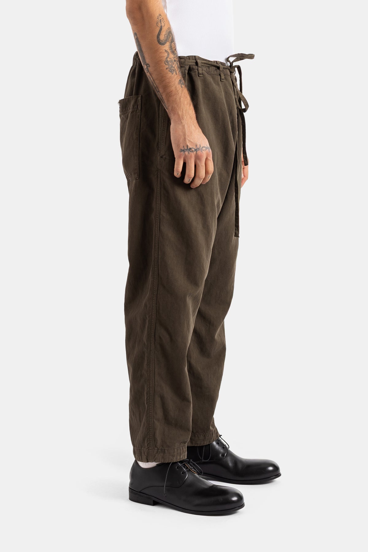Casey Casey men's khaki cotton trousers side view with elastic waist, hanging drawstrings and cargo pockets.