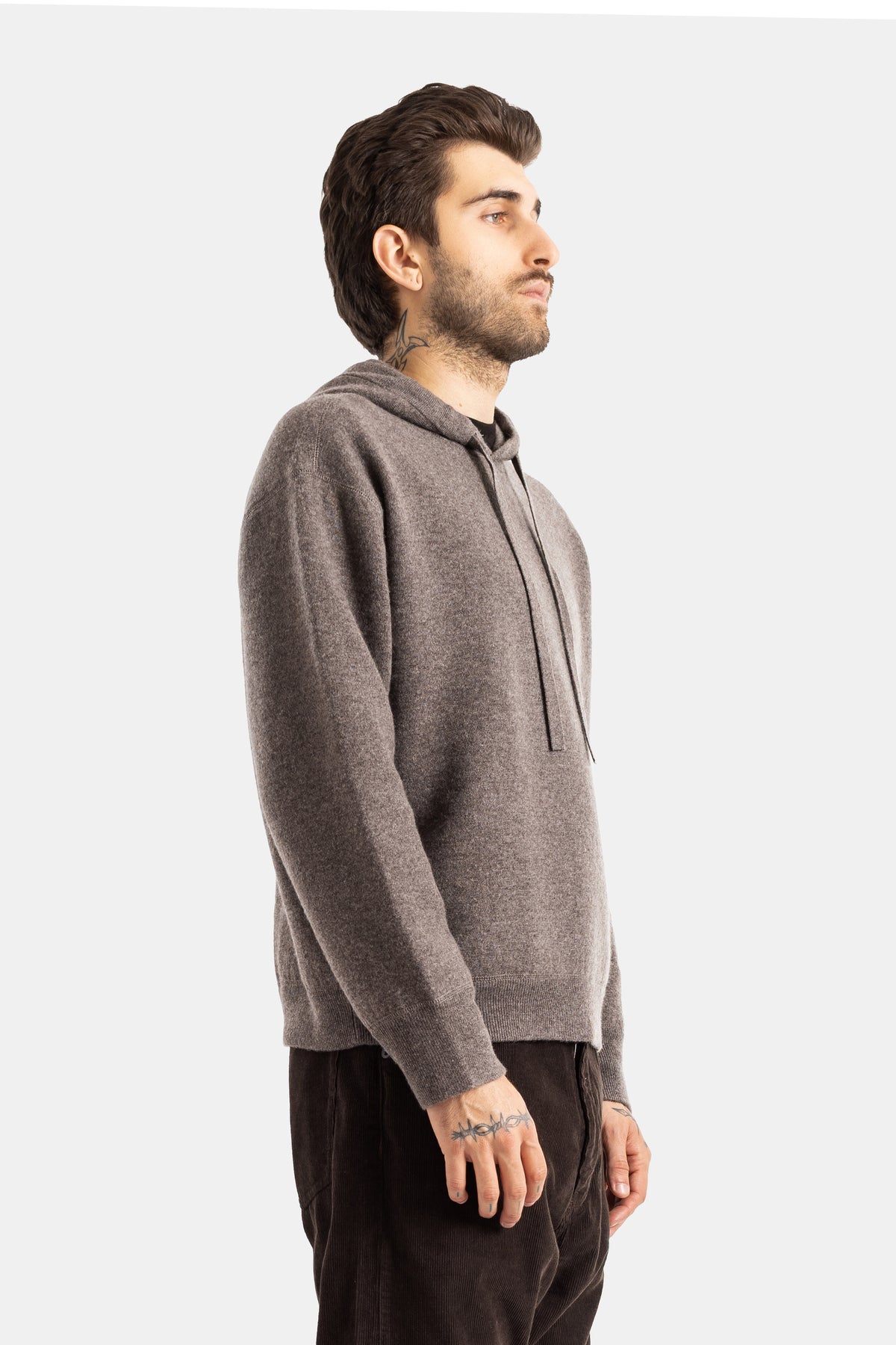 Studio Nicholson Kaschmir-Kapuzenpullover in Taupe in Seitenansicht, Boxy-Schnitt mit langen Rippbündchen-Ärmeln.