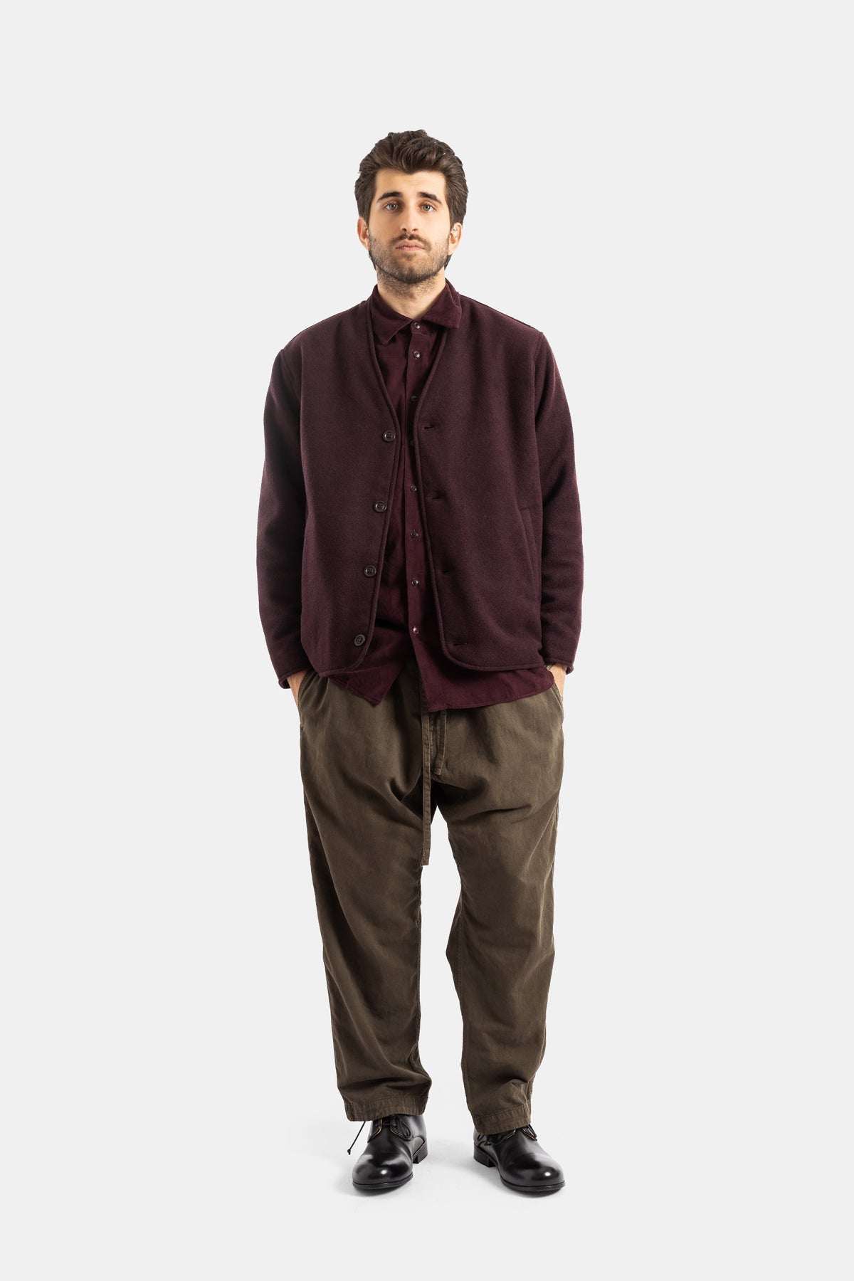 Casey Casey veste Killian laine bordeaux portée en layering sur chemise, pantalon cargo kaki et derbies noirs