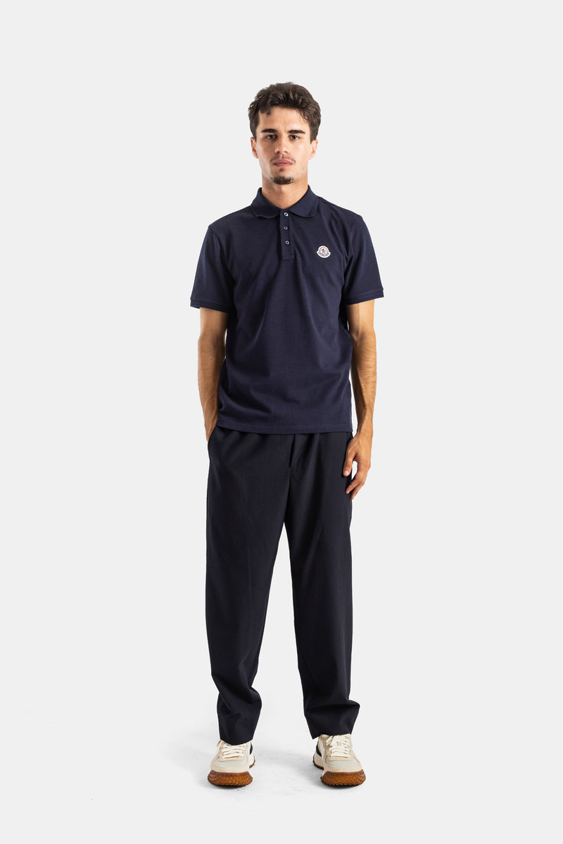 Full look with Moncler navy polo shirt, fluid trousers, white sneakers and iconic chest logo patch for men.