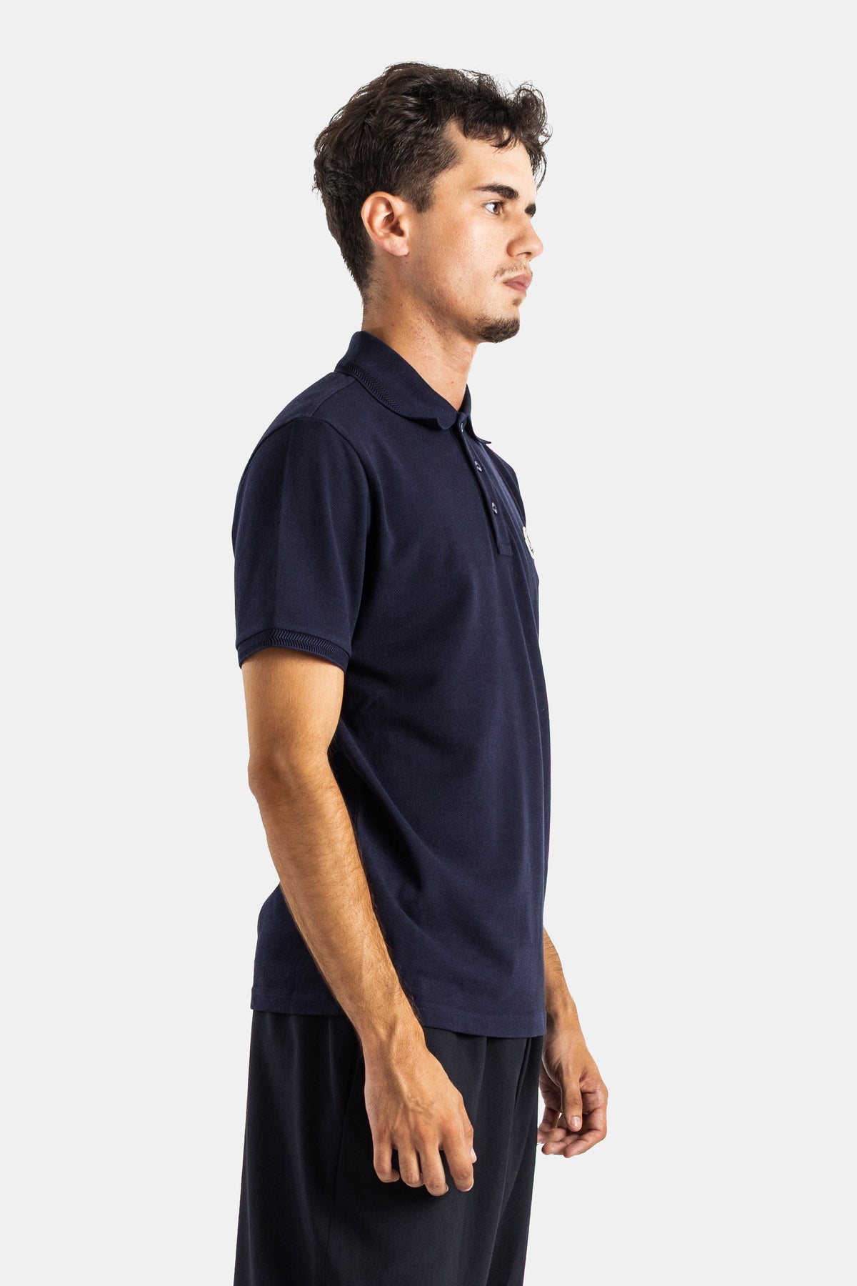 Side view of Moncler men's navy cotton piqué polo, textured fabric, tone-on-tone buttons and a straight cut.