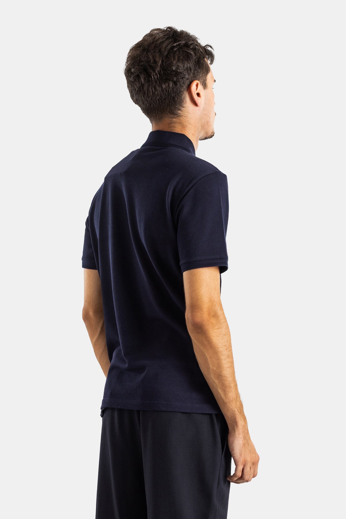 Back view of Moncler men's navy blue cotton piqué polo with a high collar, ribbed trims and short sleeves.
