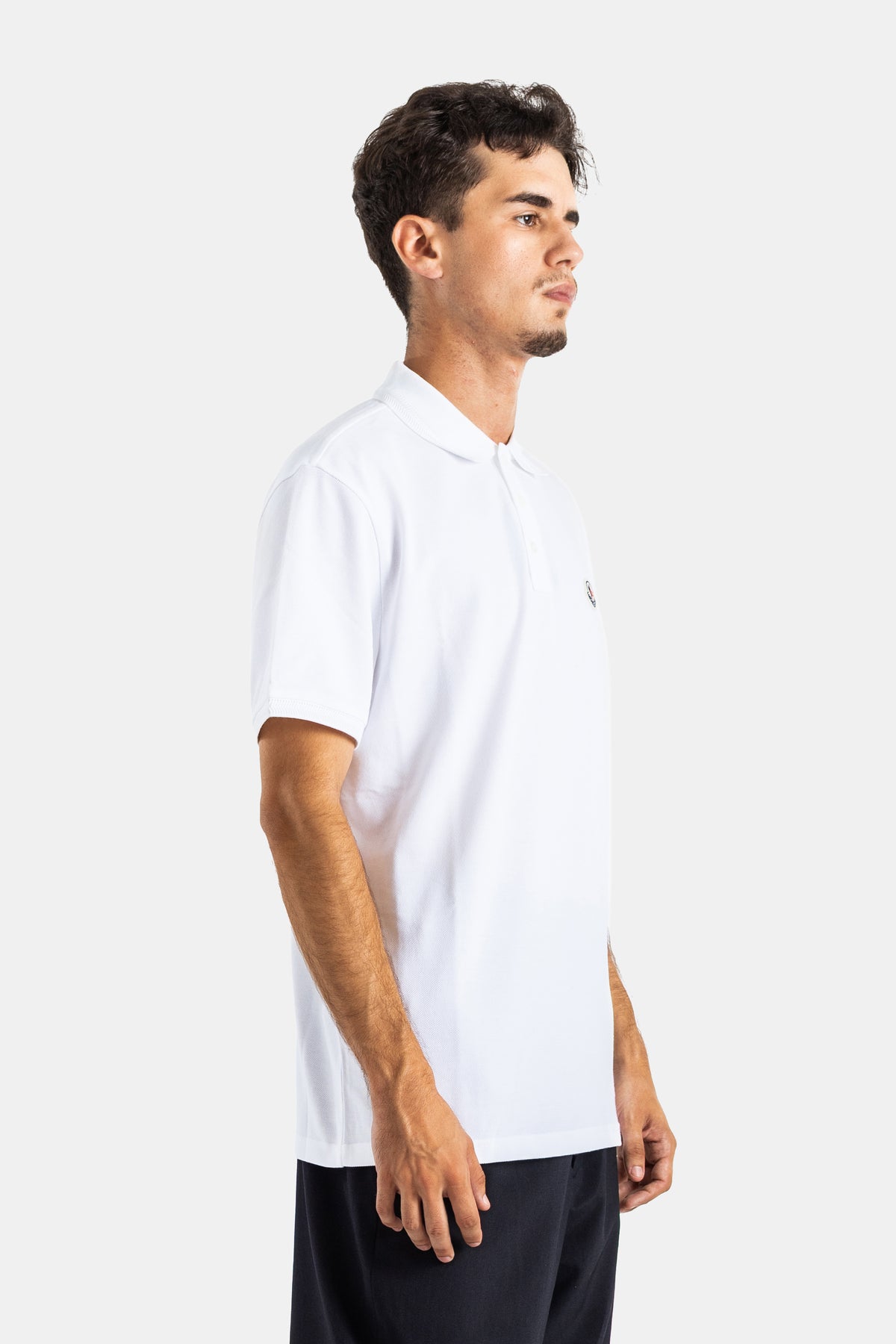 Profile view of Moncler men's white polo in cotton piqué with the signature embroidered chest logo patch.
