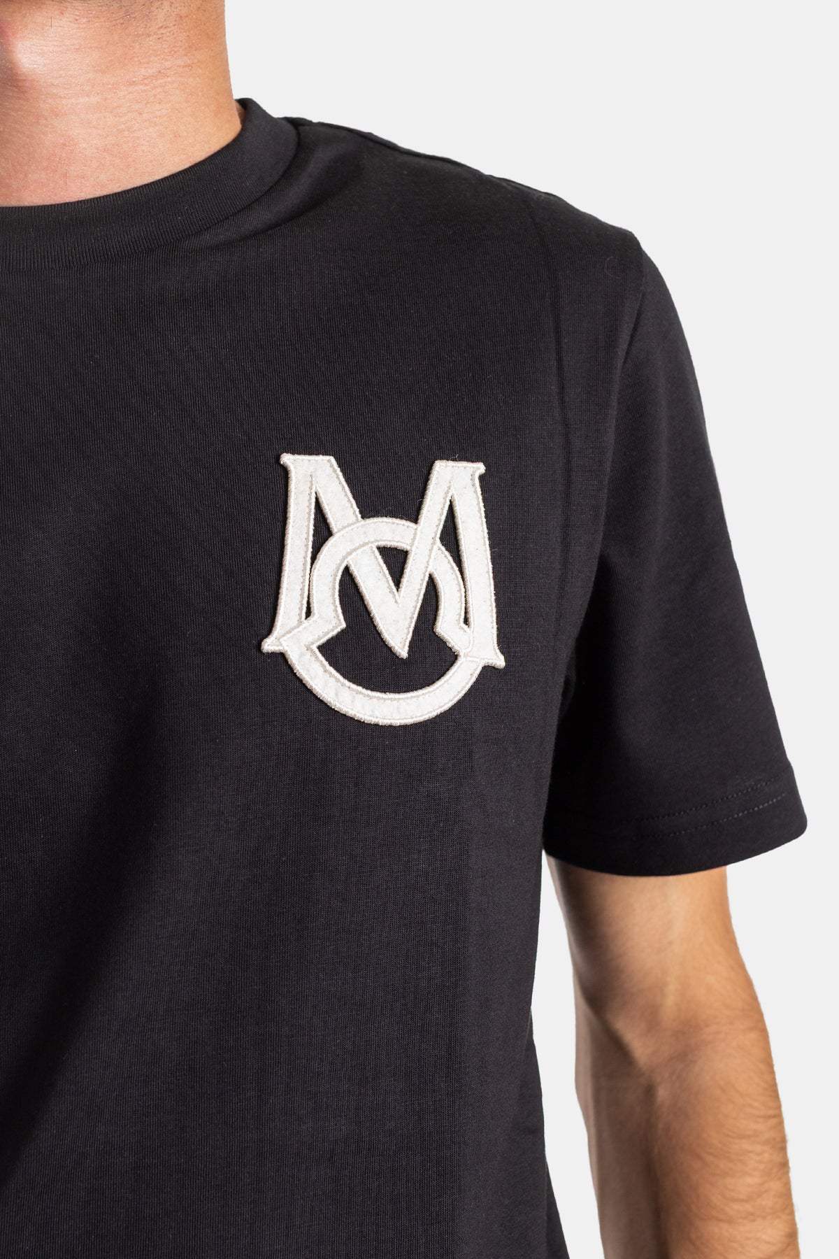 Detailed close-up of the Moncler black cotton t-shirt featuring a raised off-white embroidered monogram