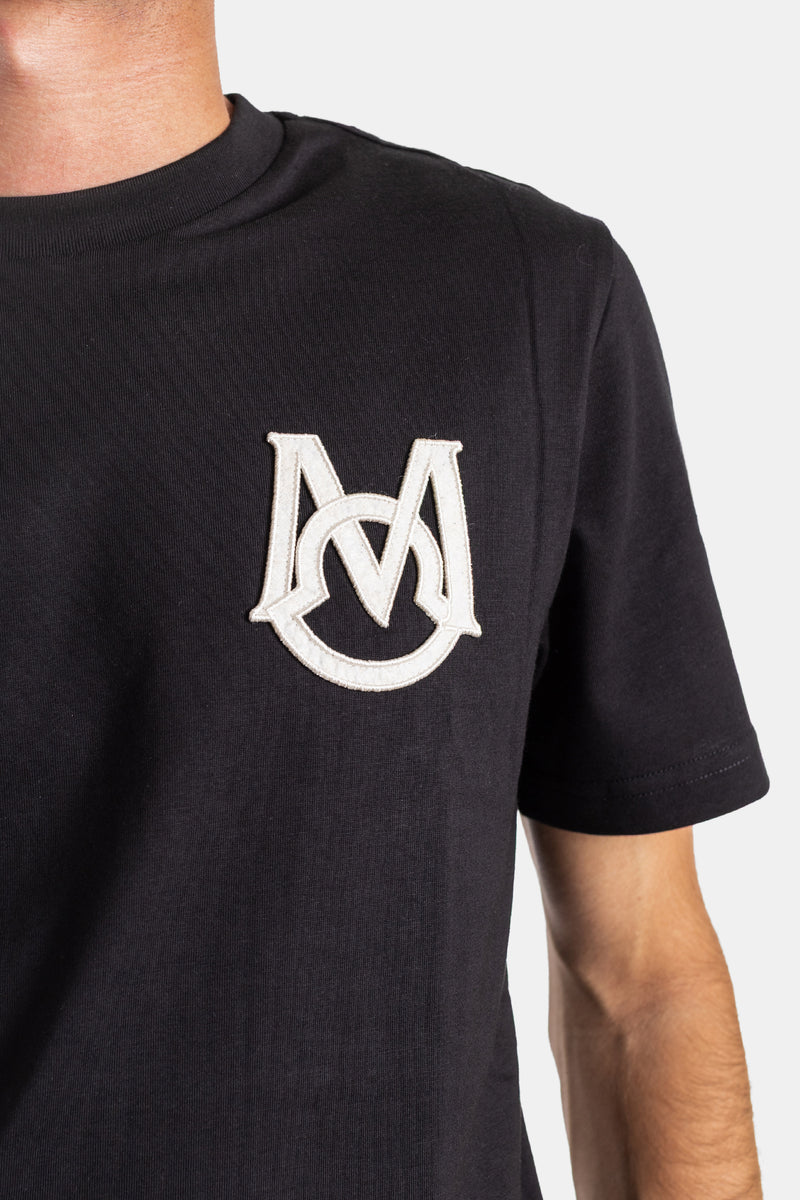 Detailed close-up of the Moncler black cotton t-shirt featuring a raised off-white embroidered monogram