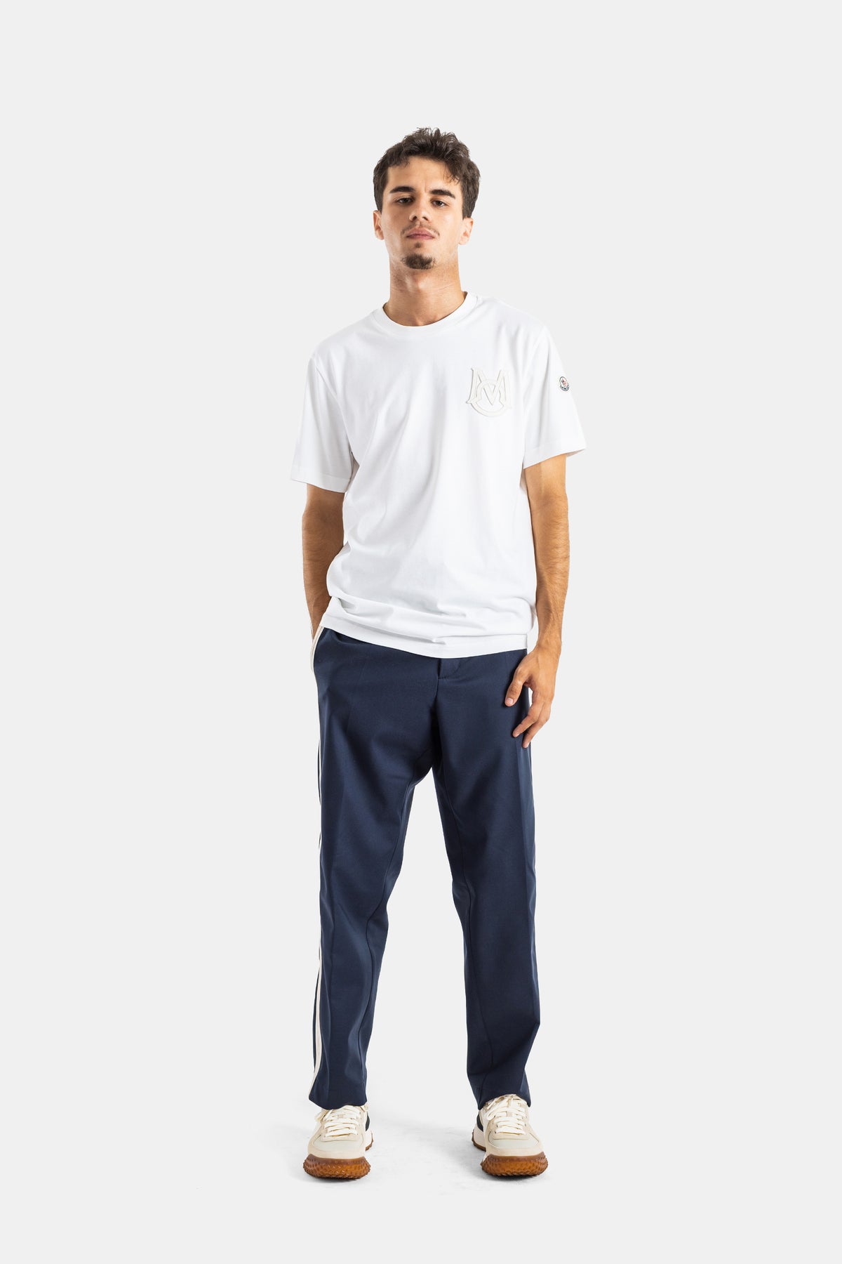 Full streetwear look featuring the Moncler men's white T-shirt paired with navy trousers and sneakers