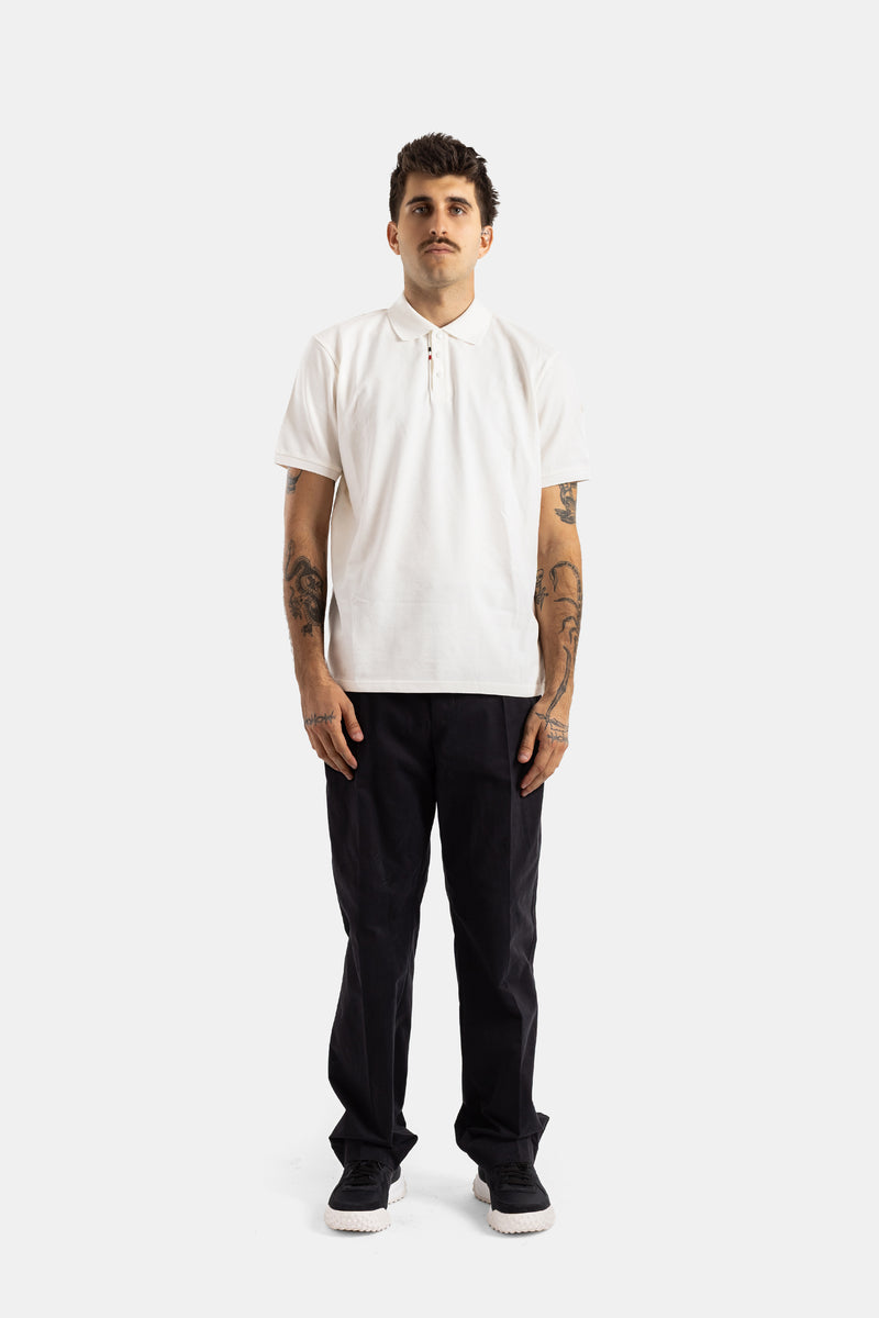 Moncler polo blanc homme port frontal pantalon noir tatouages bras visibles tenue casual chic