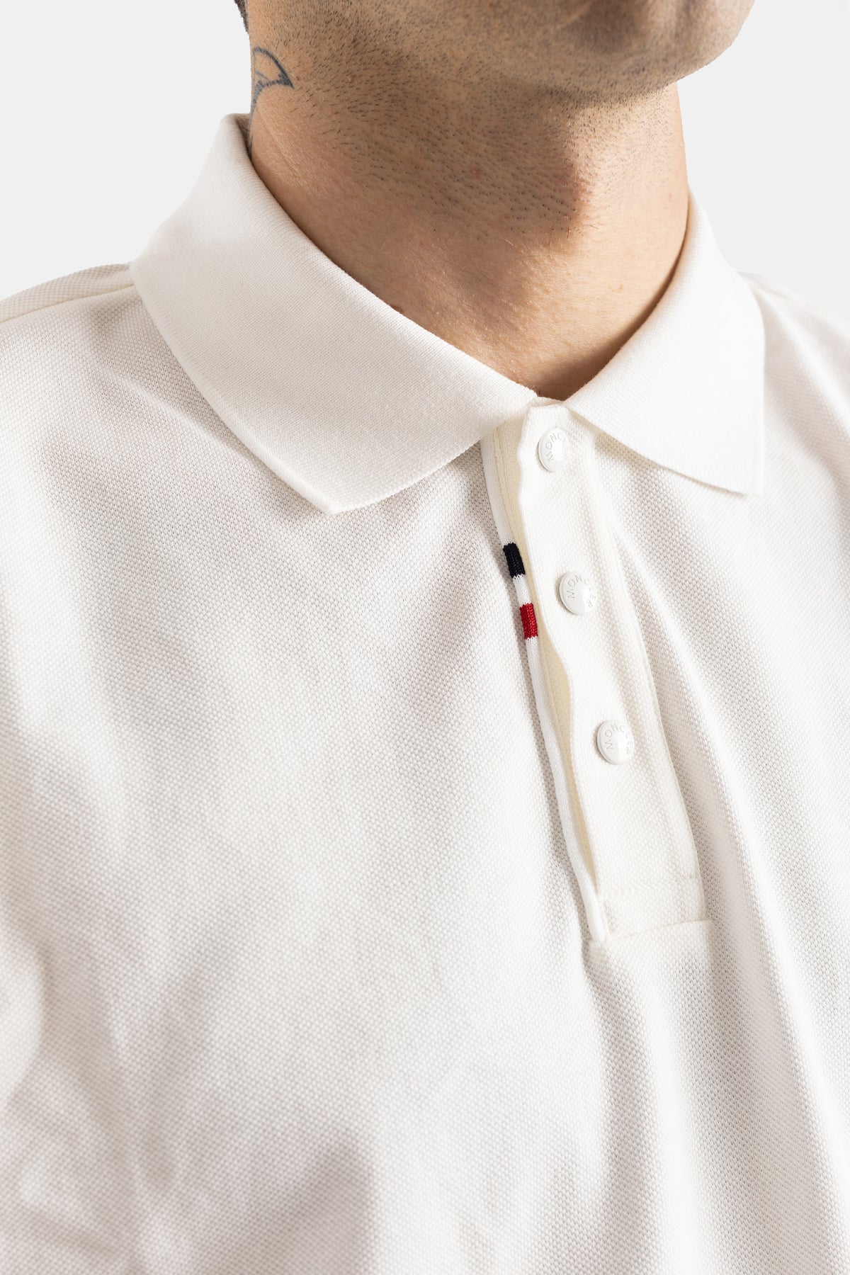 Moncler polo blanc homme gros plan col piqué coton boutons nacre liseré tricolore rouge bleu noir placket