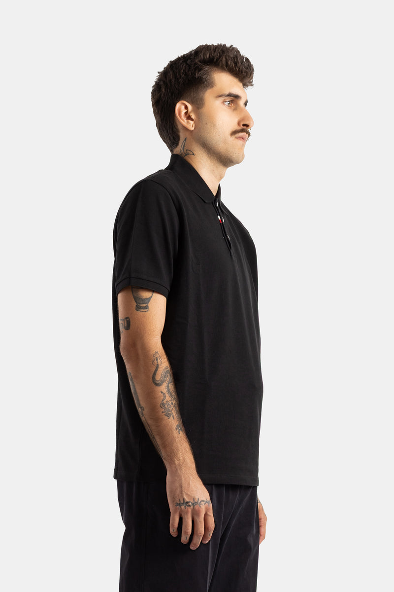 Moncler polo homme noir vue profil tatouages bras boutons tricolores tissu piqué coton stretch