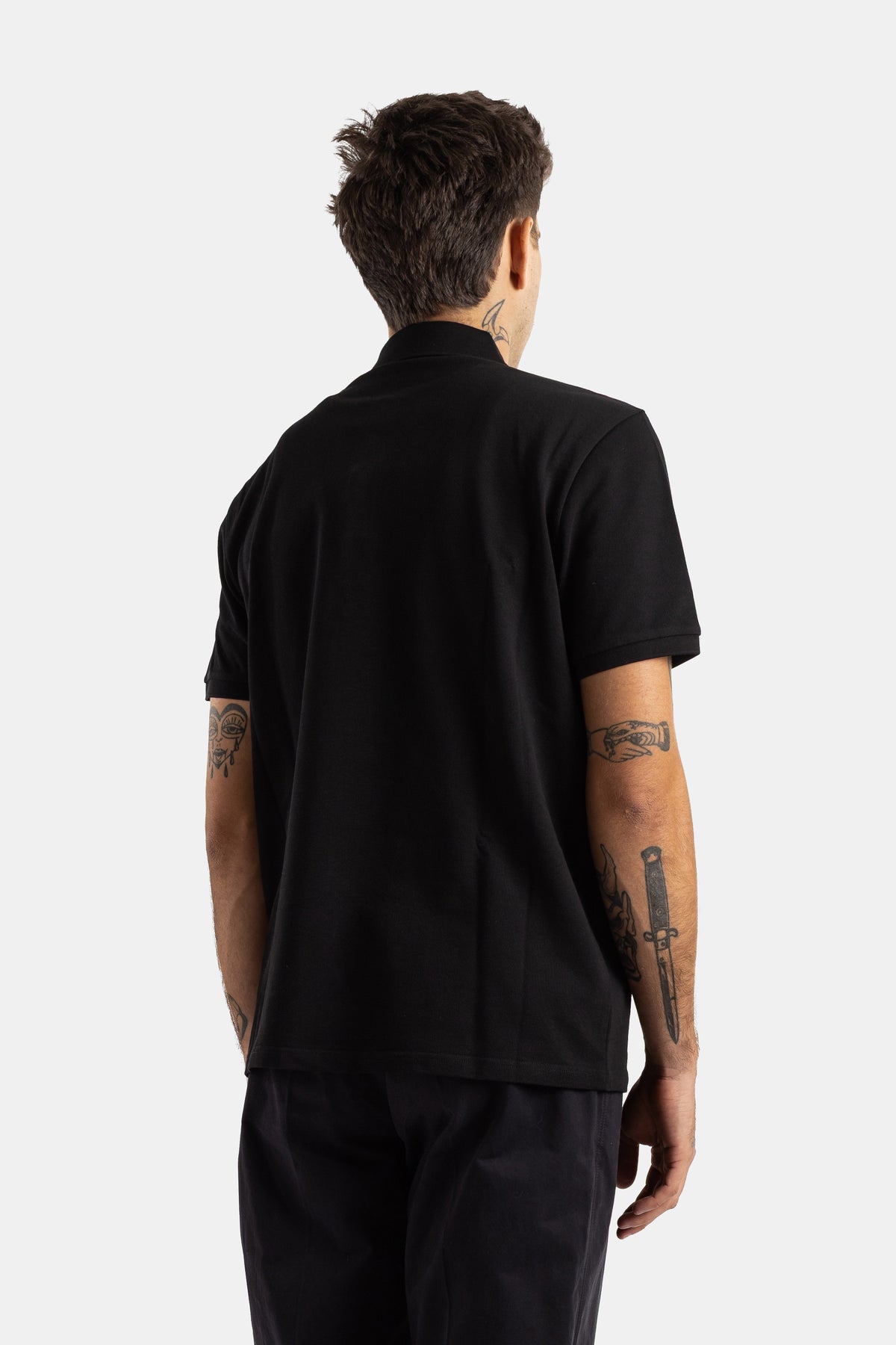 Moncler polo piqué coton noir dos vue arrière tatouages bras coupe ajustée col polo homme