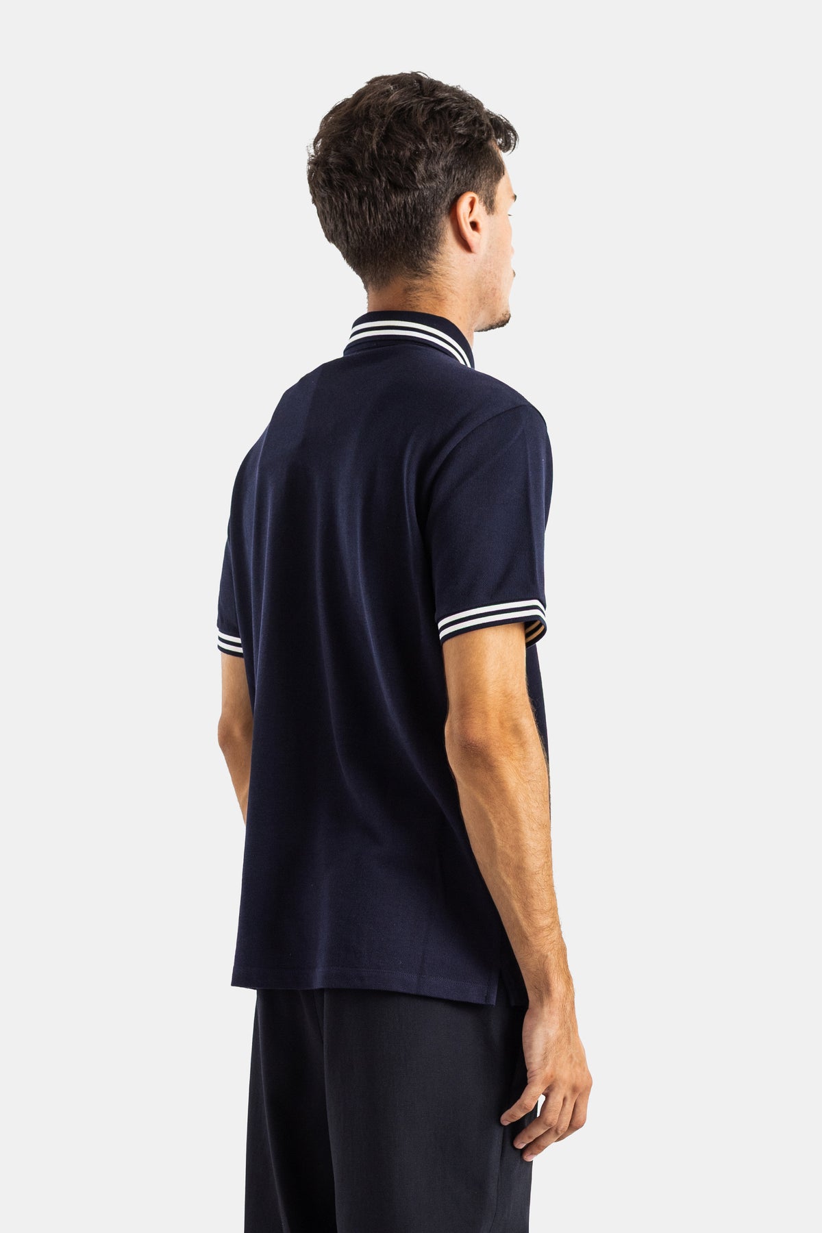 Back view of Moncler men's navy blue polo, white striped standing collar, contrasting cuffs, relaxed fit.