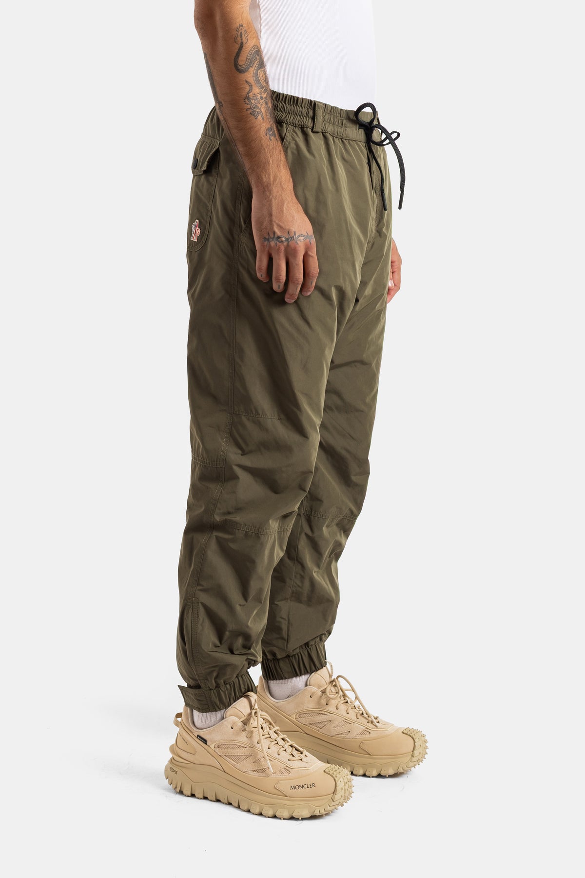 Moncler Grenoble jogger kaki profil latéral cordon noir ceinture élastiquée bas resserré sneakers beige homme