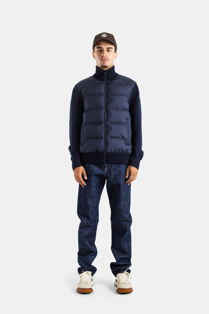 Front view of Moncler men's navy blue quilted cardigan full look with raw jeans and leather sneakers.