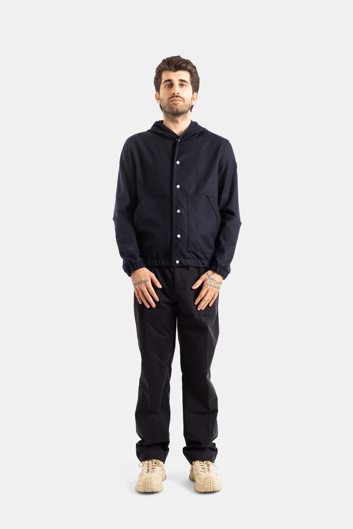 Moncler men's navy wool jacket, total navy look with matching trousers and beige sneakers, full silhouette