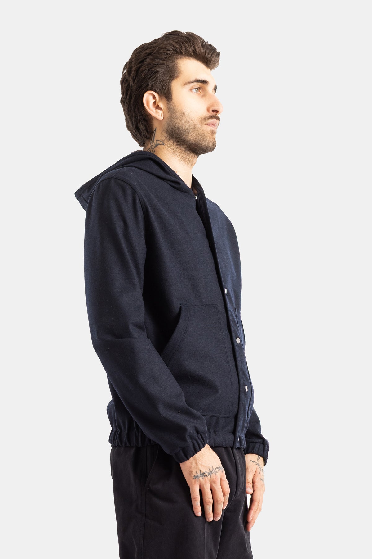 Moncler men's navy blue wool jacket shown from side profile with a structured hood and elasticated cuffs