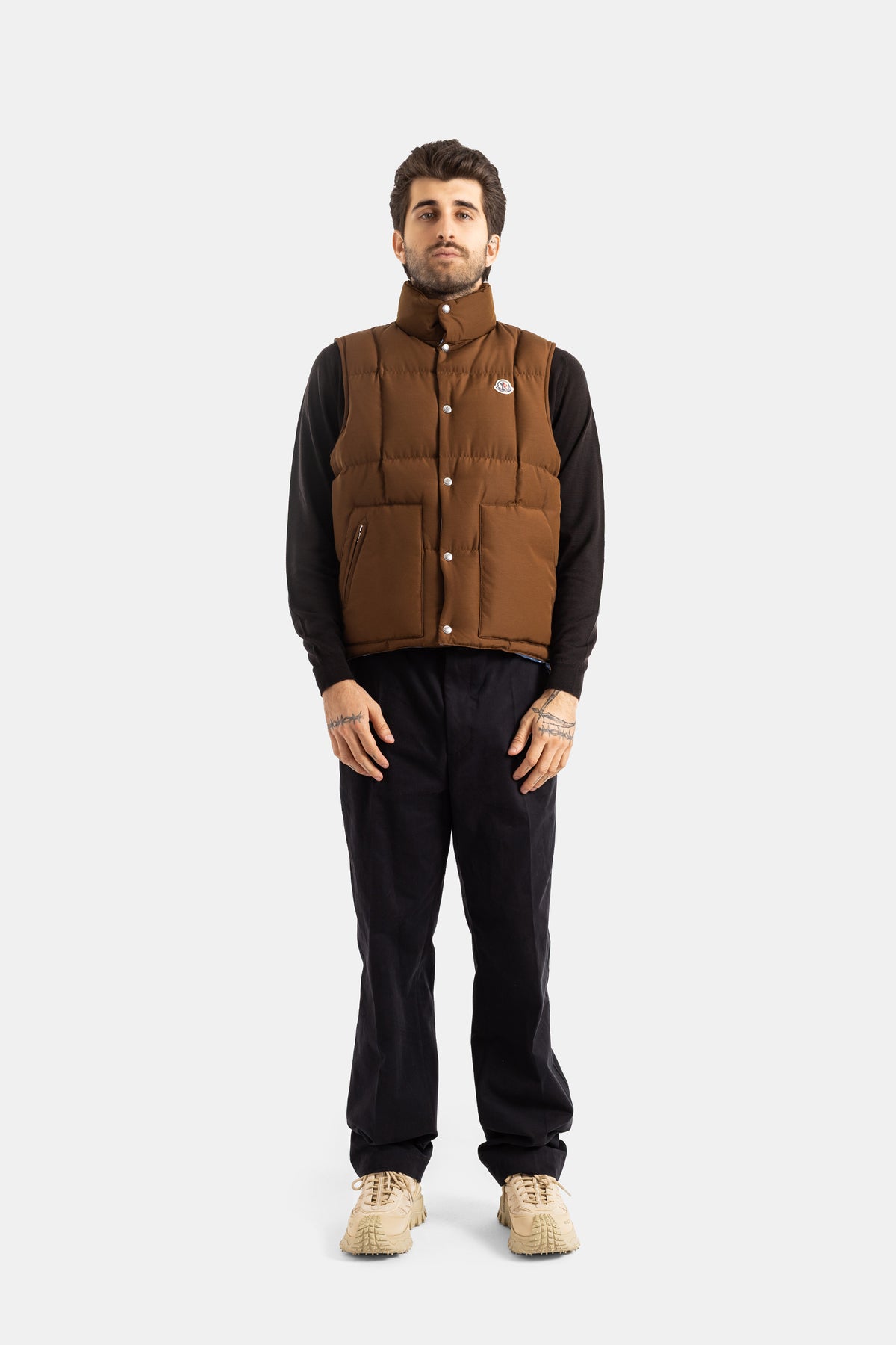 Moncler Brumelune men's brown quilted gilet styled with black sweater and dark trousers for a luxury casual look