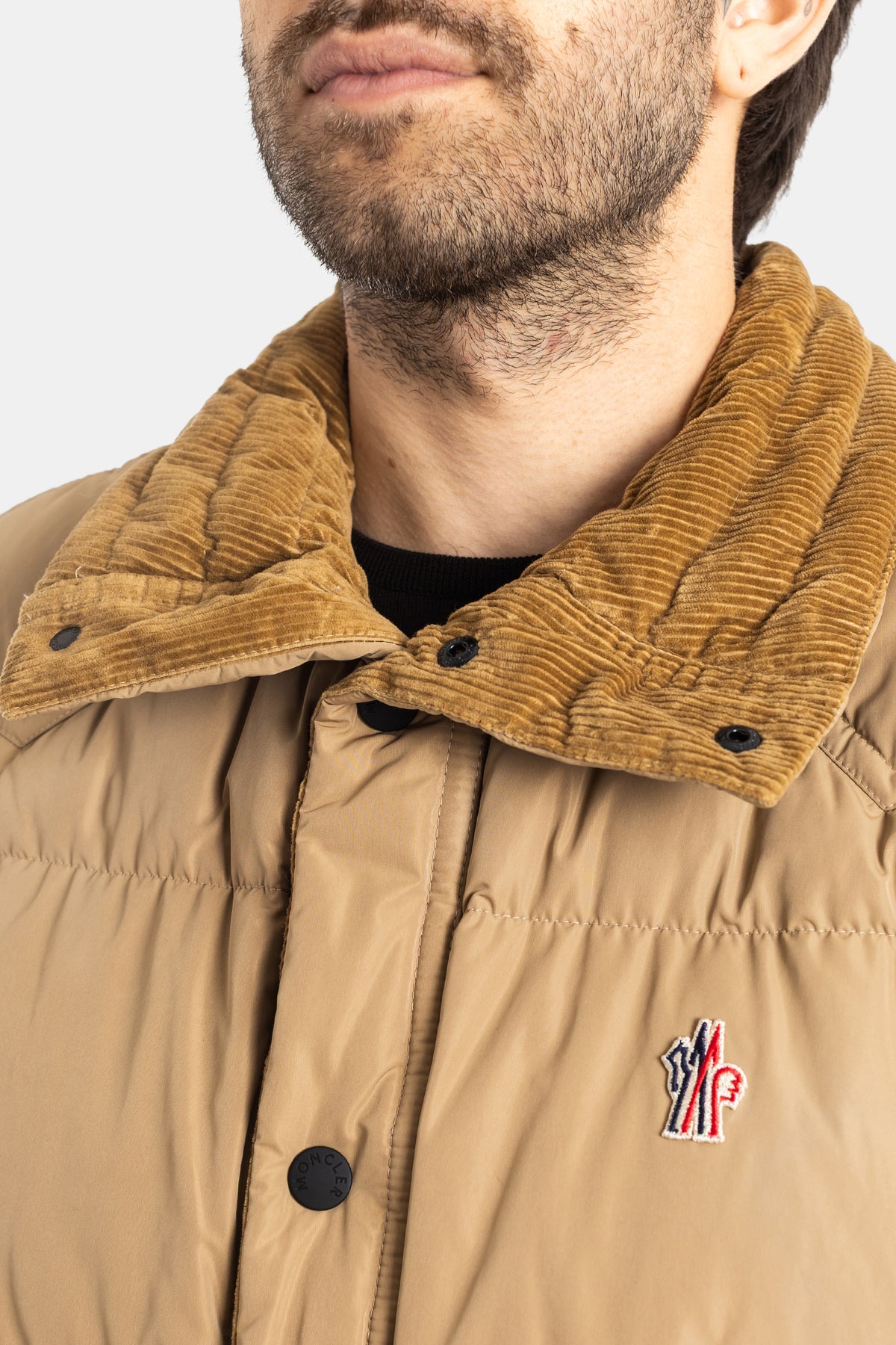 Moncler Grenoble Evans close-up on camel corduroy collar and embroidered tricolor logo patch on beige down vest.