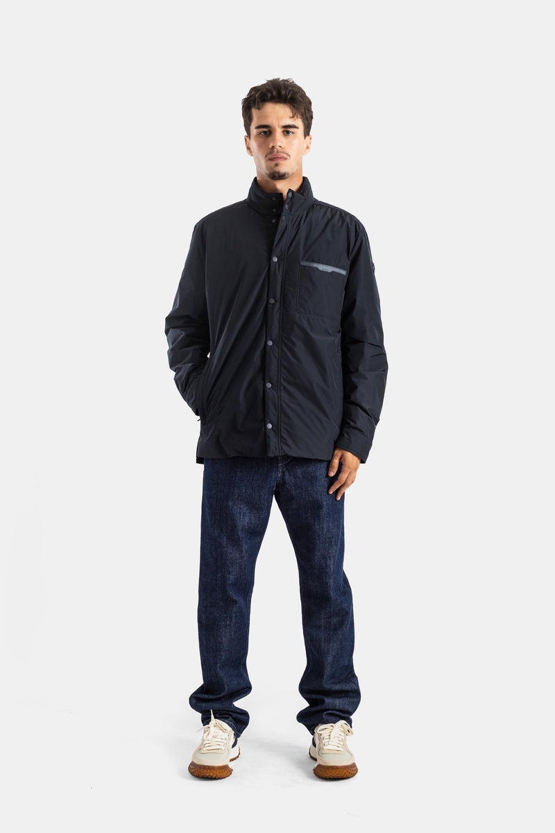 Moncler black Yndale men's down jacket in a full look with raw jeans, white sneakers, reflective detail.