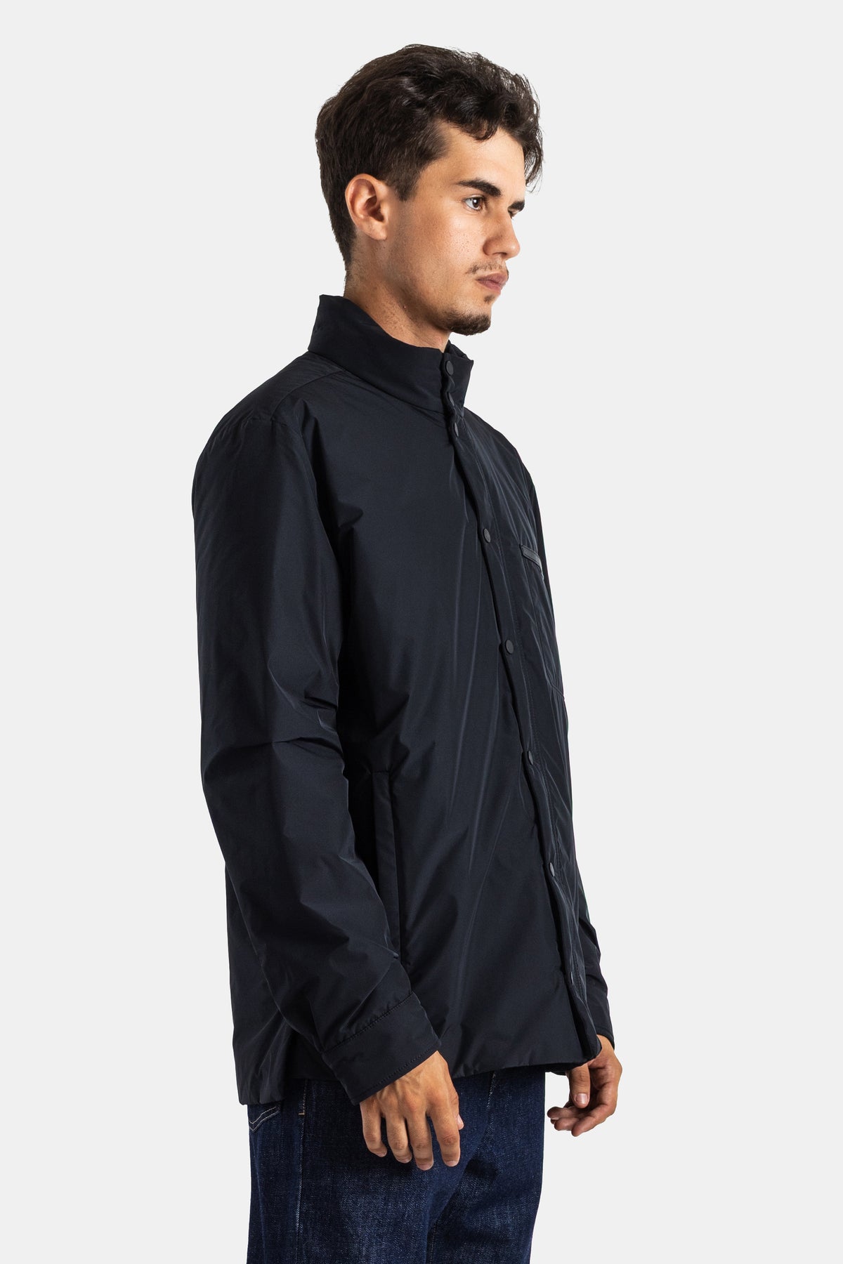 Casaco Moncler Yndale de homem de perfil, comprimento a meio da coxa, mangas compridas e punho ajustado preto.