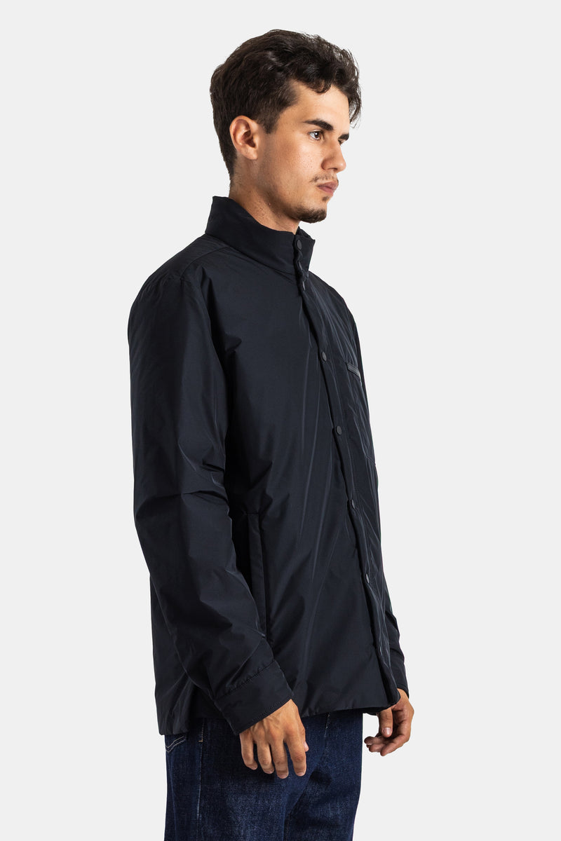 Casaco Moncler Yndale de homem de perfil, comprimento a meio da coxa, mangas compridas e punho ajustado preto.
