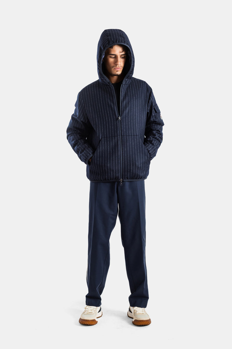 Moncler Ceze men's full silhouette wearing the hood in tennis pinstripe fabric with beige rubber sole sneakers.