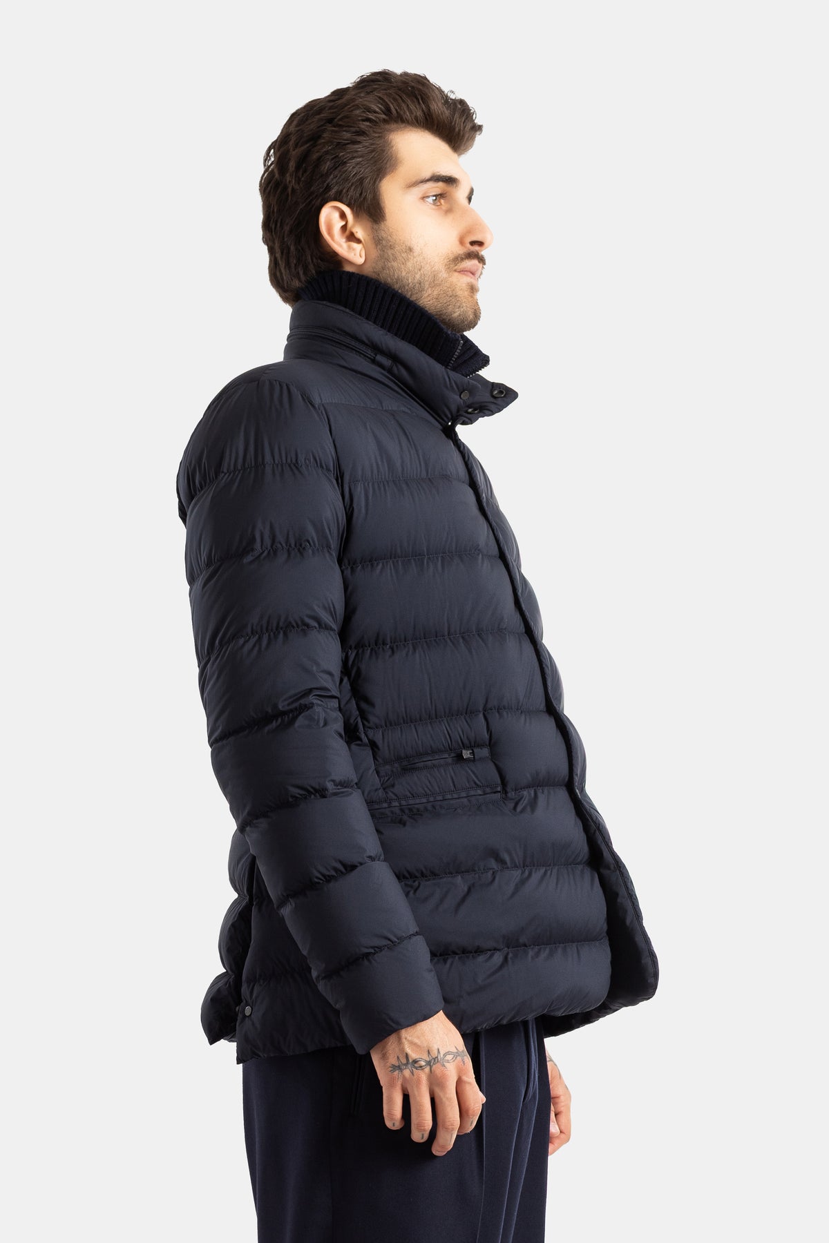 Moncler Elarune men's down jacket side profile with horizontal quilting and knit collar in navy blue.