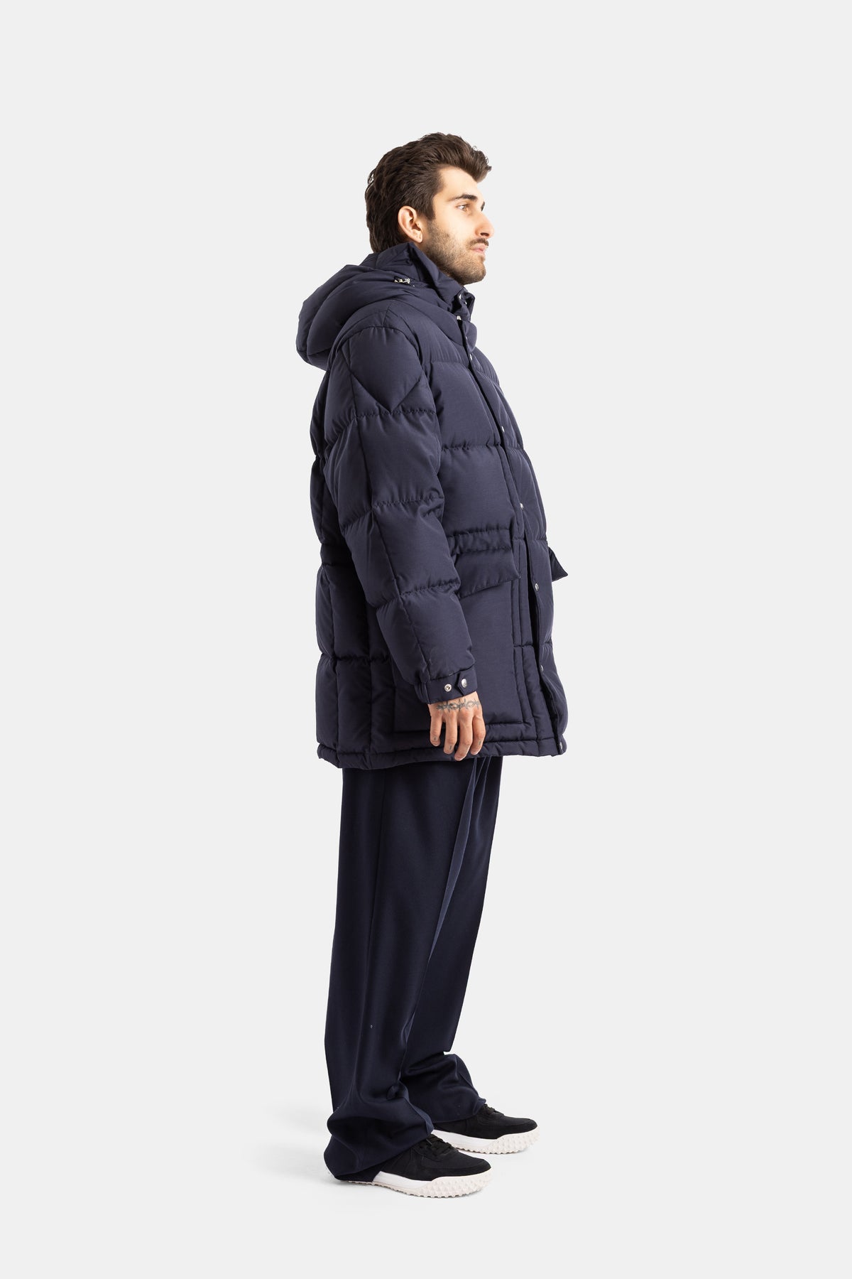 Moncler Sylmara side view of men's long down jacket in navy blue with generous hood and geometric quilting